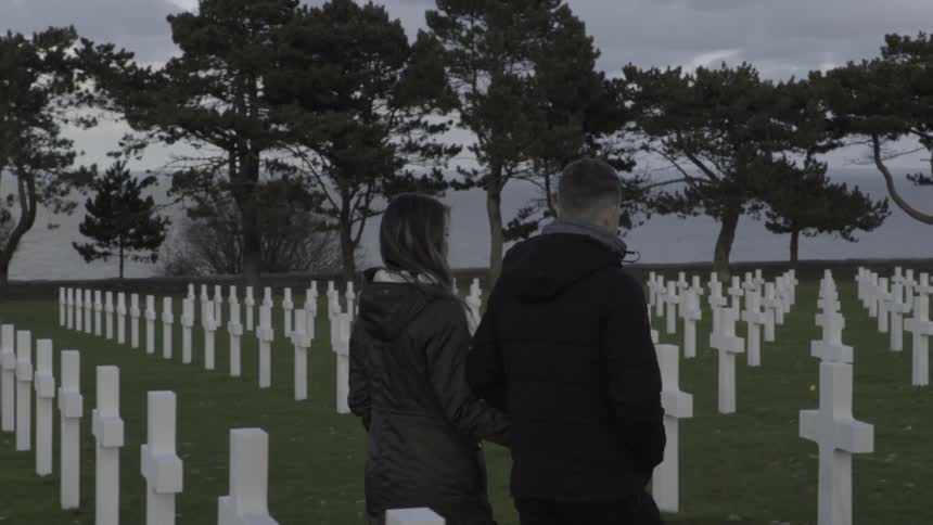 Two people walk through a graveyard together