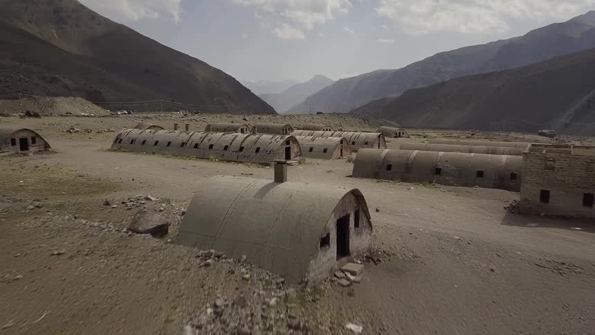 The field by a mountain is lined with barracks