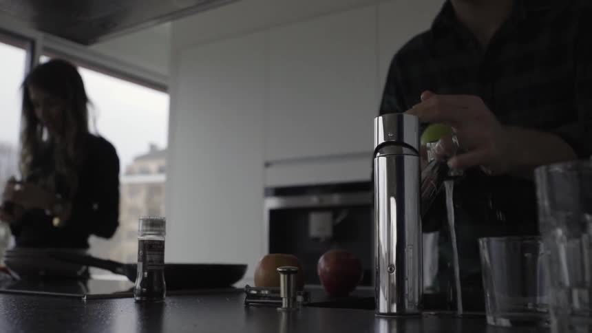 A man washes fruit at a kitchen sink