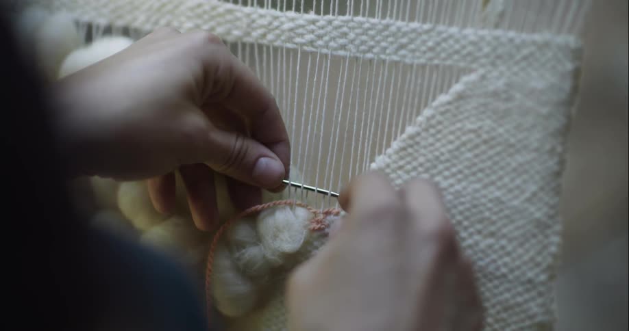 A person weaves on a loom