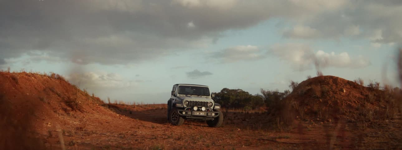 A motocross rider performs an epic jump in slow motion over a Jeep on a rustic dirt track