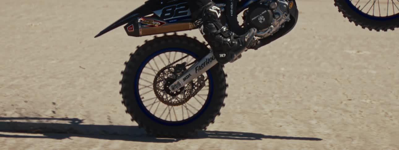 Slow motion close-up of a motocross bike's rear tire spinning during a burnout in the desert