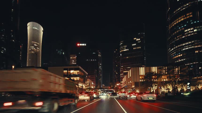 A POV shot driving through the illuminated streets of a modern metropolis at night, surrounded by towering skyscrapers and city traffic