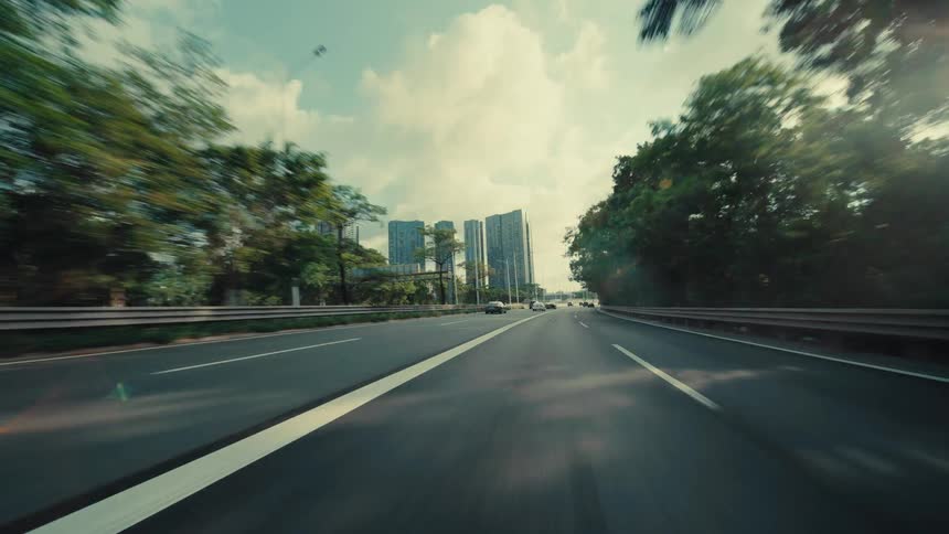 A cinematic low-angle POV shot captures a car speeding down a multi-lane highway, with lush green trees blurring past as a modern city skyline appears on the horizon