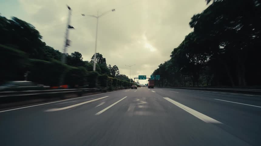 Dramatic point-of-view shot of a car driving at high speed on a busy highway under a cloudy sky