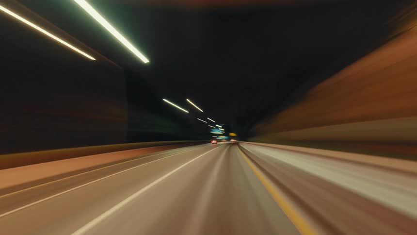 A futuristic POV hyperlapse of a high-speed drive through city highways and tunnels at night, creating mesmerizing light trails