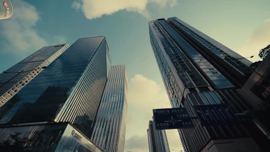 A stylized low-angle view slowly pulls back from a group of towering glass skyscrapers in a modern city's financial district