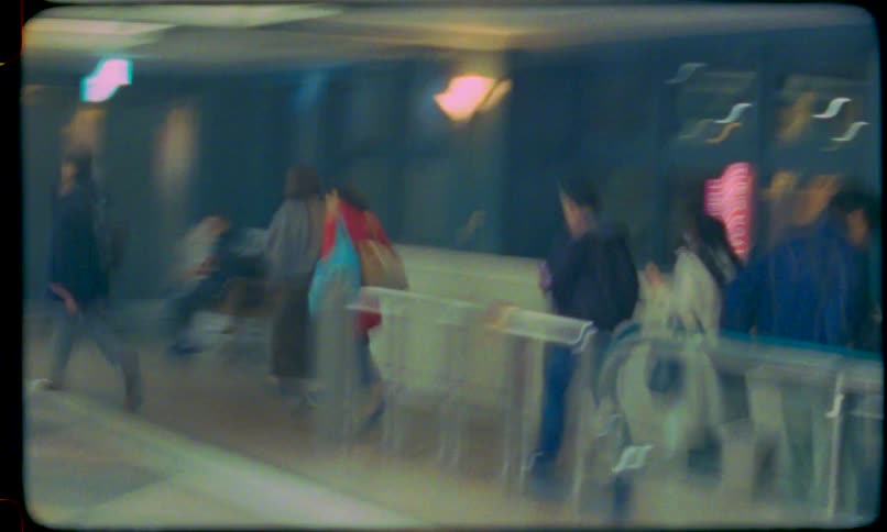 An abstract and blurry vintage film captures the fast-paced movement of people on a travelator in an airport terminal