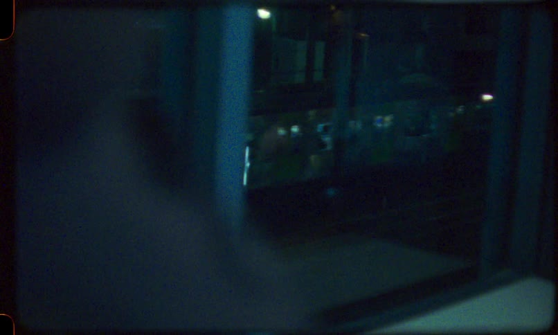 Grainy vintage footage shows a blurry view of a passing subway train at night from a moving window