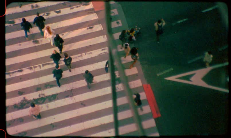 Nostalgic film-style overhead shot of people crossing a city street