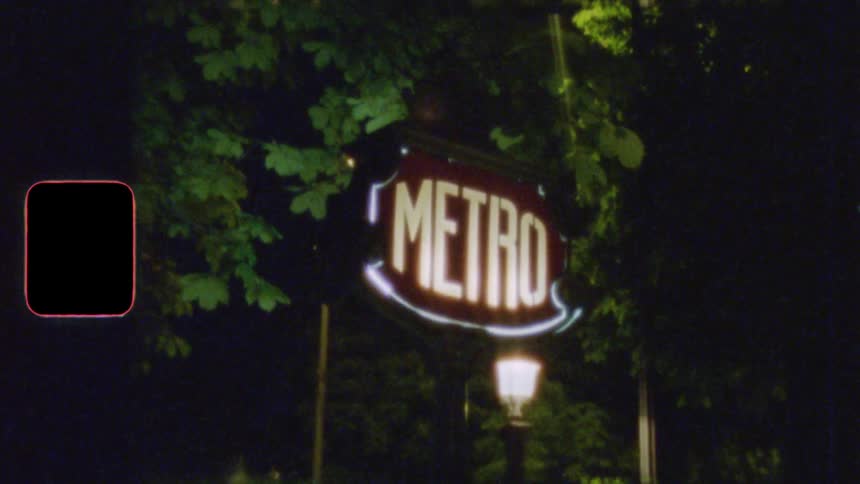 An authentic Super 8 film captures a glowing red and white Paris Metro sign at night, surrounded by trees