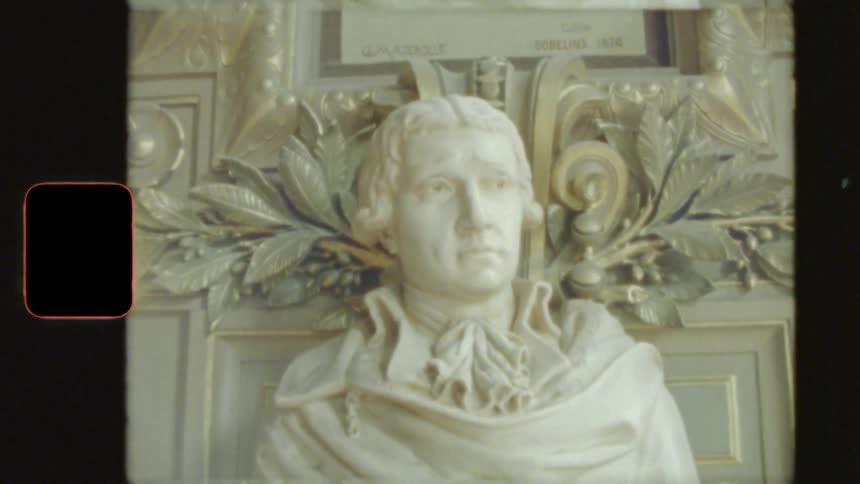 Archival 8mm footage showcases a detailed marble bust of a man against a decorative wall