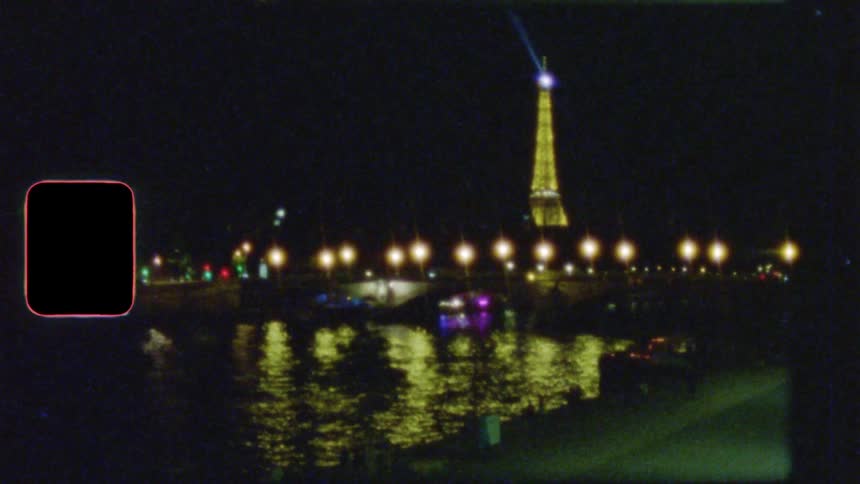 A dreamy, vintage film shot of the Eiffel Tower and the Seine river at night, with city lights reflecting on the water