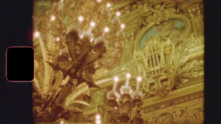 Vintage 8mm film captures the ornate golden ceiling and glowing chandeliers of a historic European opera house or palace