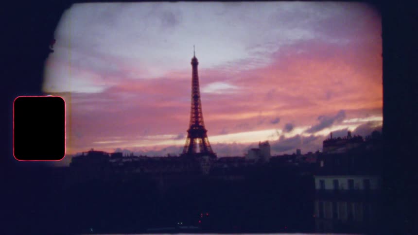 Vintage 8mm footage reveals the Eiffel Tower in Paris silhouetted against a beautiful pink and orange sunset sky