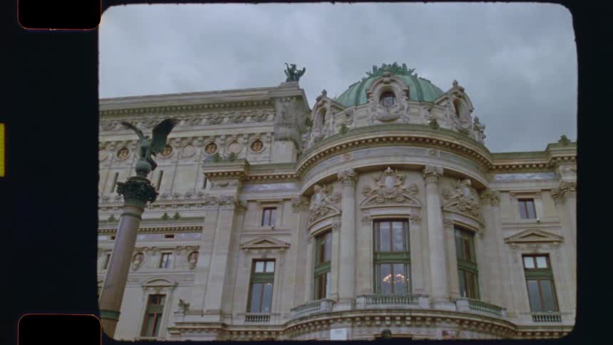 A vintage film-style shot slowly pans across the ornate Beaux-Arts facade of the Palais Garnier in Paris under a cloudy sky