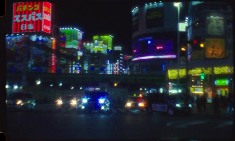 A dreamy, vintage film shot pans across a busy Tokyo intersection at night, capturing the glow of neon signs and moving traffic