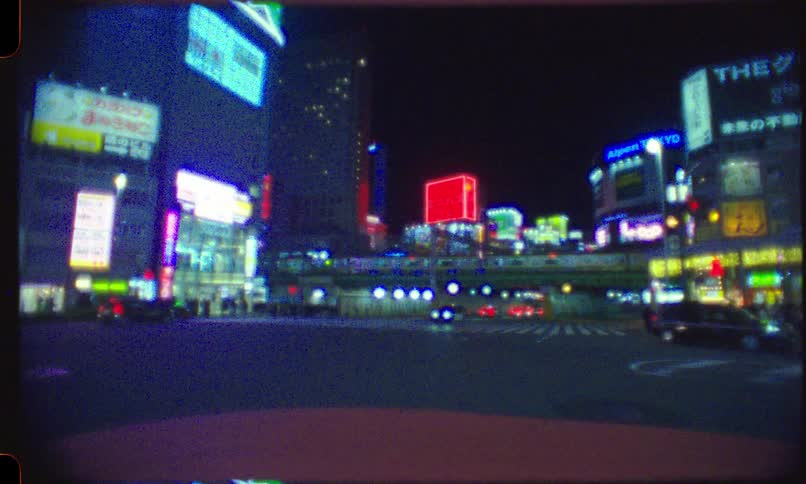 Super 8mm film look of a bustling Tokyo intersection at night, with vibrant neon lights and passing cars and trains