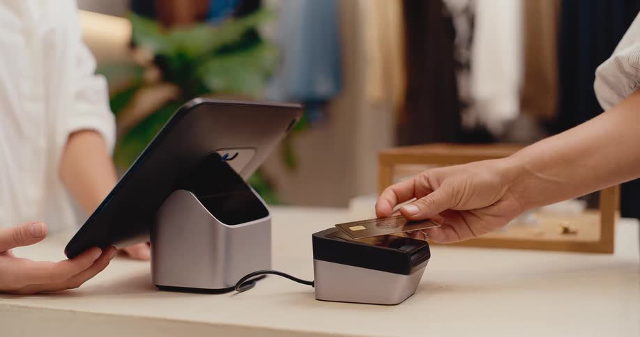 Close-up of a customer making a contactless payment by tapping their credit card on a modern payment terminal in a store