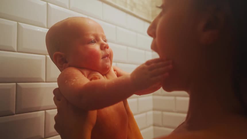 A loving mother holds her newborn baby in her arms while they share a warm shower together