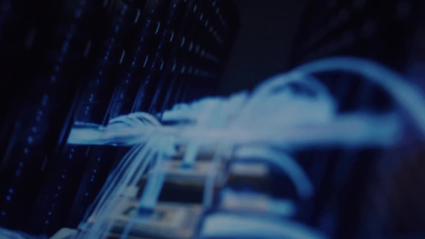 Glowing blue fiber optic cables transmit data through a server rack in a futuristic, out-of-focus macro shot