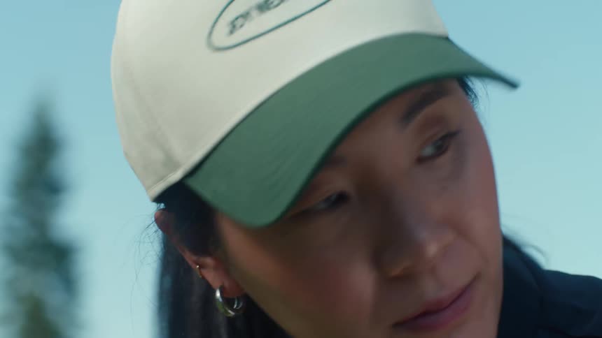 Close up slow motion shot of an Asian woman in a baseball cap concentrating outdoors