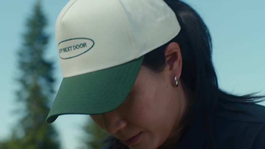 A close-up of a woman in a baseball cap concentrating intently outdoors on a sunny day
