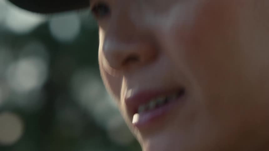 Slow motion extreme close-up of a female golfer's focused eyes and her hand gripping a golf club on a sunny day