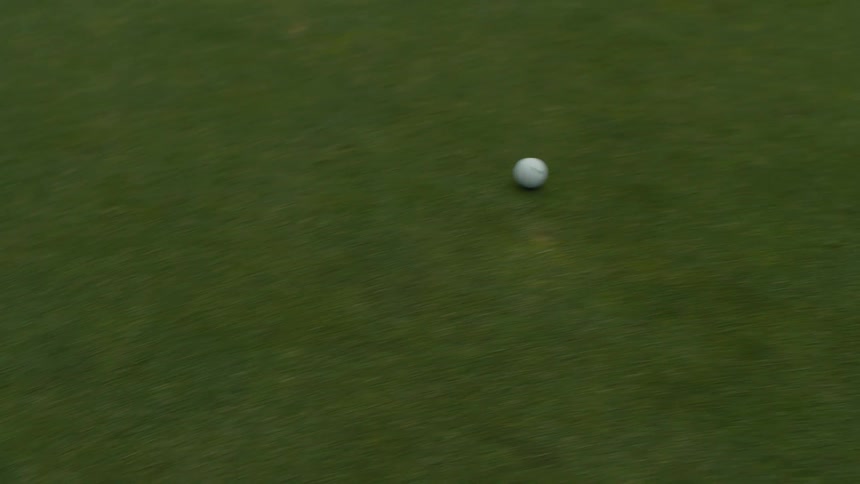 An overhead close-up shows a white golf ball rolling across a manicured putting green