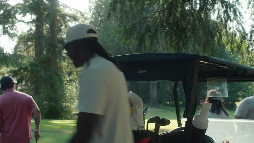 Friends socialize by a golf cart before heading to the tee box on a sunny course