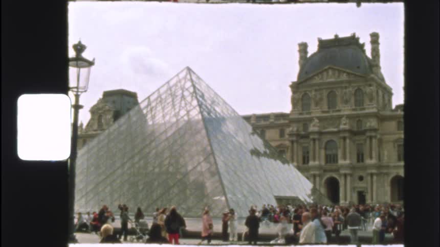 Vintage film footage captures a crowd of tourists exploring the iconic Louvre Pyramid in Paris