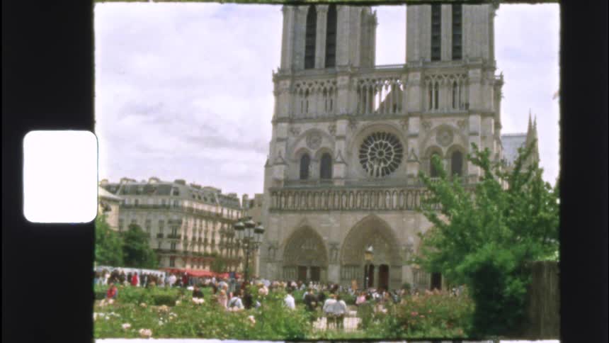 An archival 8mm film captures a classic view of the Notre-Dame Cathedral in Paris, with crowds of tourists in the foreground