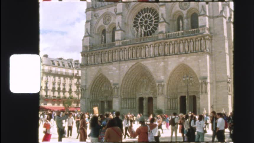 A nostalgic 8mm home movie tilts down the famous facade of the Notre-Dame Cathedral in Paris, France