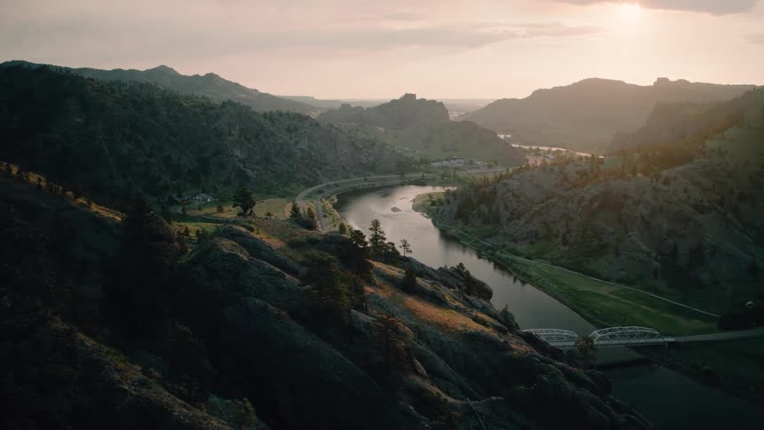 A winding river and a highway glowing in the warm sunset light of a mountain valley