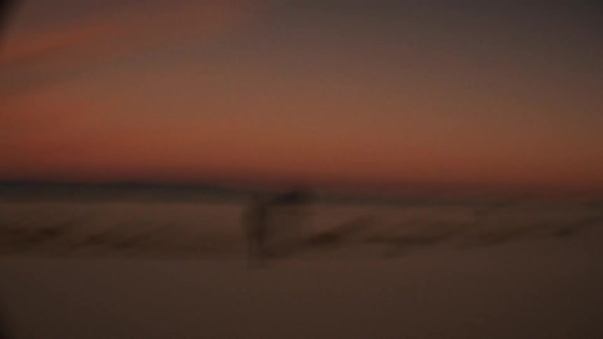 A blurry and abstract shot of a person wandering through a vast desert during a beautiful sunset
