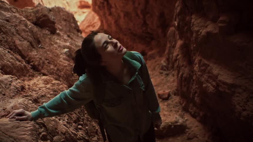 A happy female adventurer takes a moment of pure bliss inside a stunning red rock slot canyon