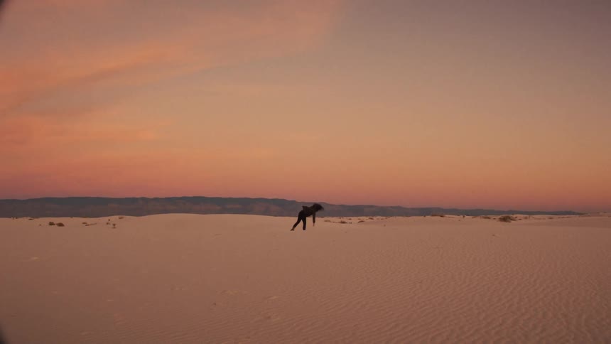 A person feels free as they walk and do a cartwheel across the vast white sand dunes during a beautiful sunset