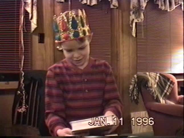 A happy young boy wearing a colorful crown receives a gift on his birthday in this nostalgic 1996 home video
