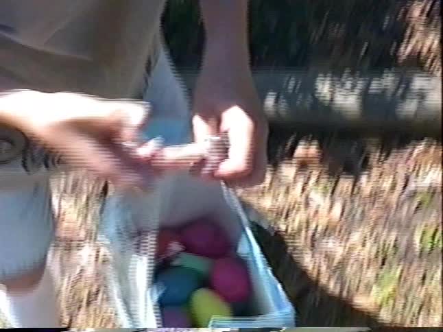 A young boy searches for colorful Easter eggs hidden in the bushes and puts them in his bag during an outdoor hunt