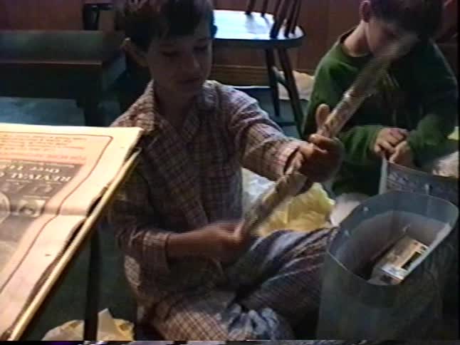 Two young brothers in their pajamas excitedly go through their gift baskets full of toys and candy