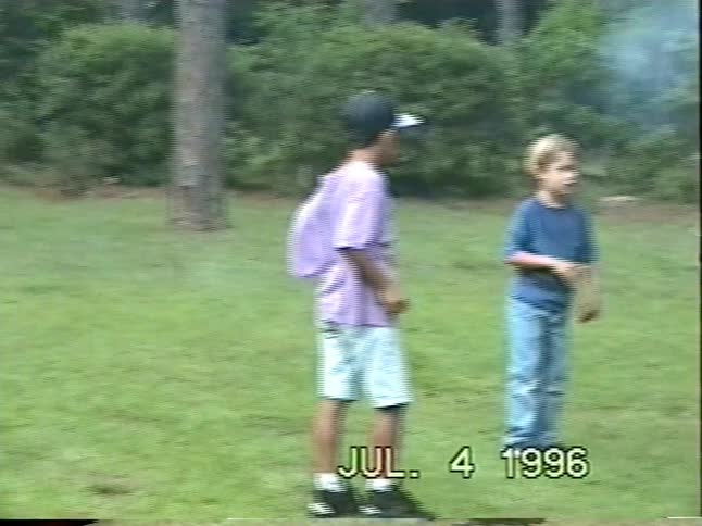 A father and his two young sons enjoy lighting sparklers and fireworks together in their backyard on the Fourth of July, 1996