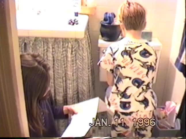 Vintage footage from 1996 shows a boy in Batman pajamas opening a Hot Wheels car gift in the bathroom while his sister watches