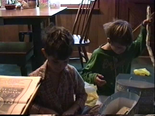 Two excited young boys open their Easter gift bags full of candy and toys on the floor of their home