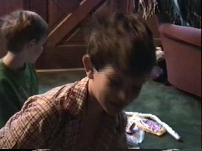 Two young brothers in their pajamas excitedly open presents and toys on the floor of their home