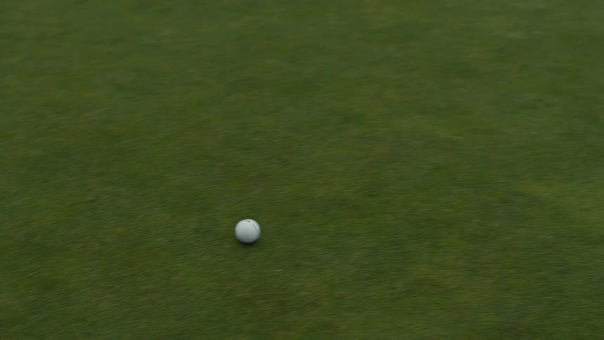 High-angle tracking shot of a golf ball rolling across a manicured green