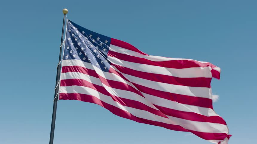 An American flag flutters gracefully in the wind against a vibrant blue sky