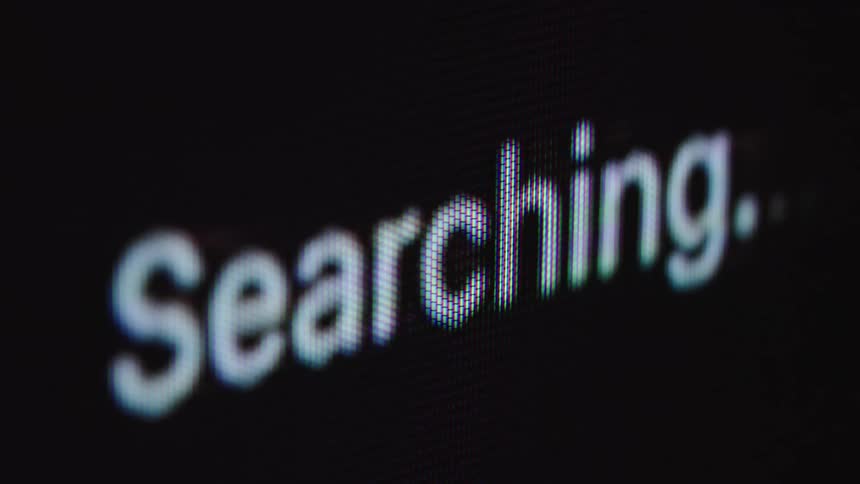 A macro close-up shot shows the word 'Searching...' with a blinking ellipsis on a black digital screen