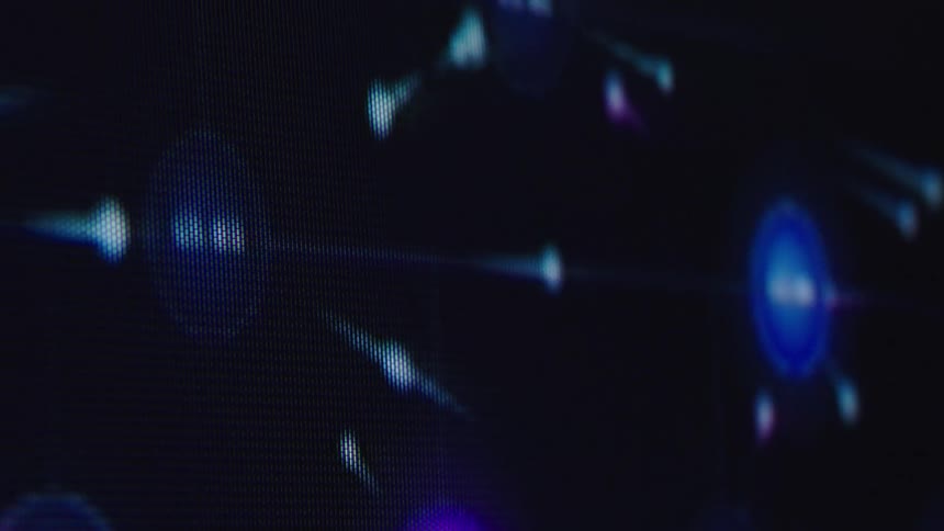 A macro shot captures an abstract animation of glowing particles and nodes forming a complex digital network