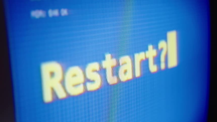 A close-up of a retro computer screen shows a flickering 'Restart?' message that glitches and turns to TV static