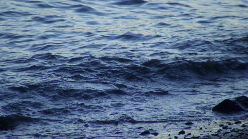 Super slow-motion footage captures the calming movement of dark blue water rippling towards the shore